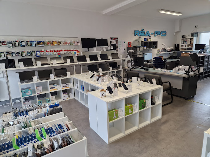 Vue intérieure de la boutique RÉA-PC à Rethel, montrant des ordinateurs, des téléphones et des accessoires en exposition